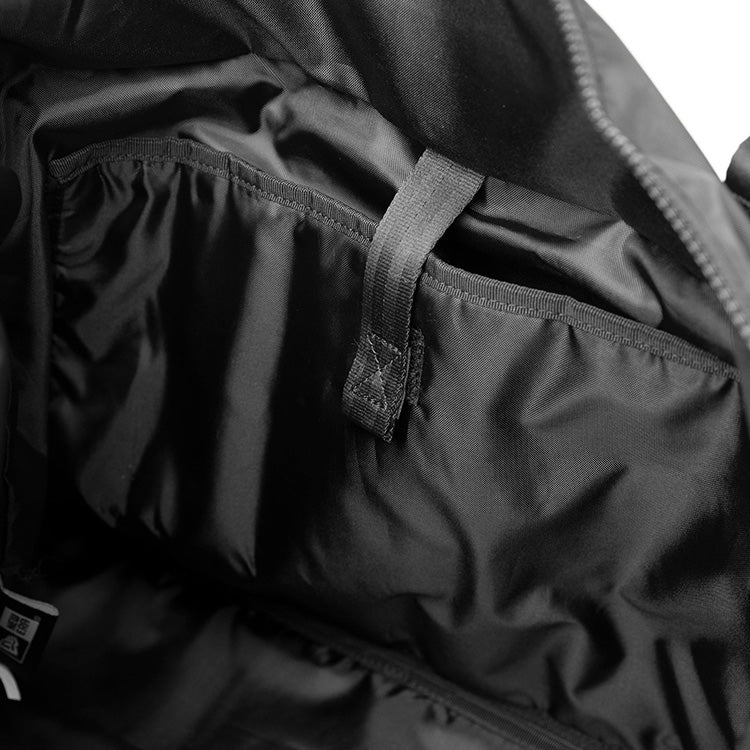 Interior view of a black New Era gym tote bag with a lined main compartment and a wide slip pocket with hook-loop strap.