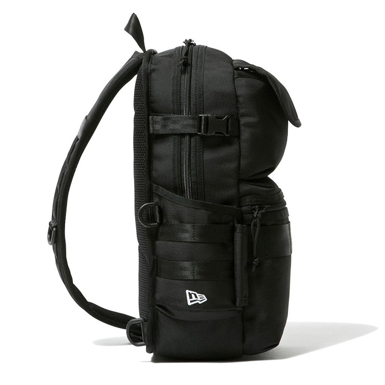 Side view of black New Era sling body bag with zip compartments, utility straps, D-rings, and padded shoulder strap.
