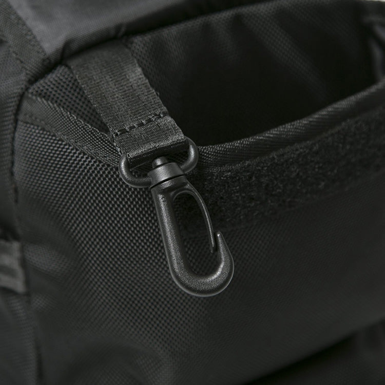Close-up of a black plastic swivel snap hook attached to a webbed nylon strap on a black bag.