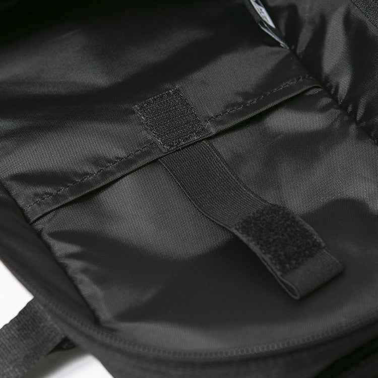  Close-up of the interior lining of a black bag, showing a slip pocket with an elastic strap and a hook-and-loop closure for securing contents.