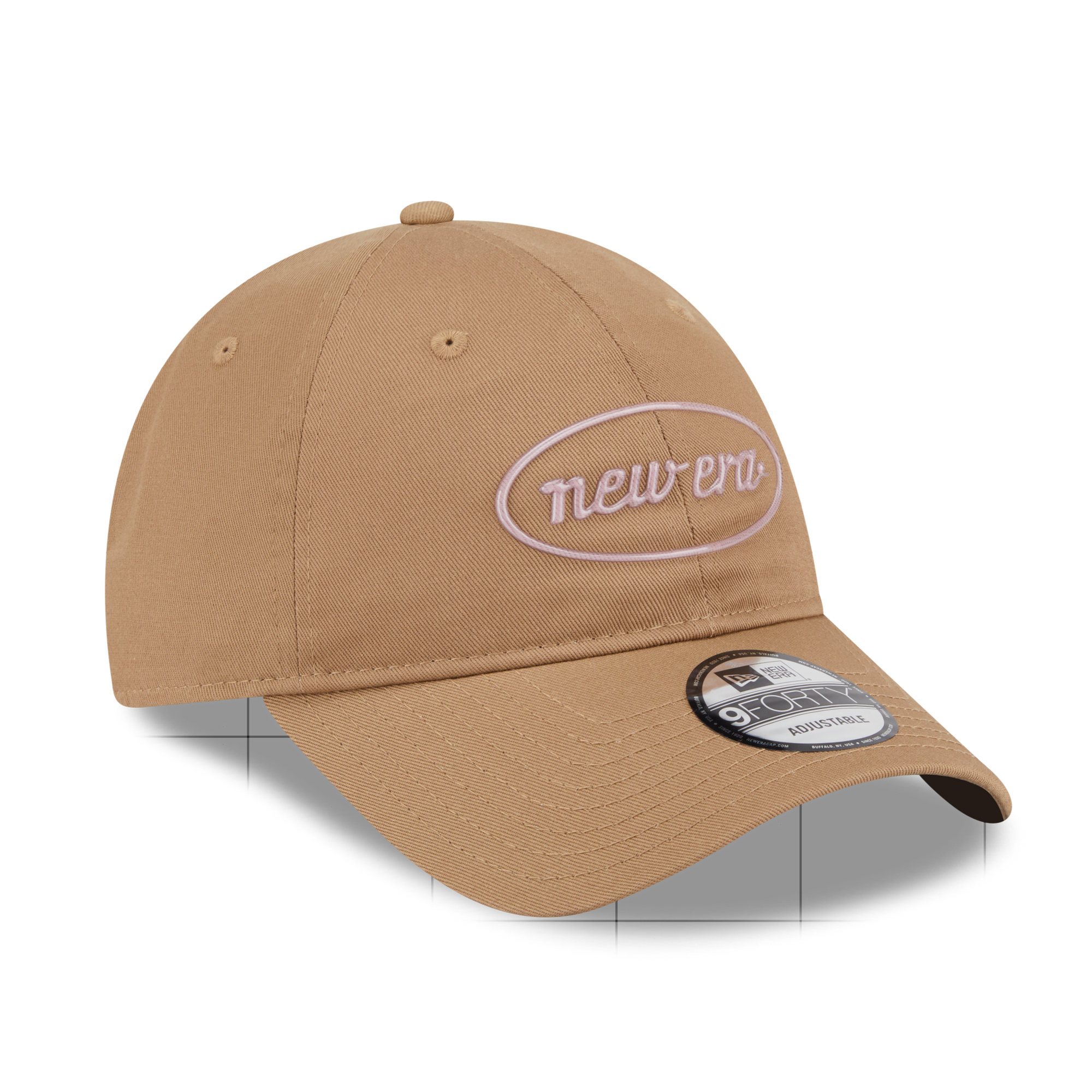 A tan New Era 9FORTY adjustable baseball cap with a white embroidered oval logo on the front and a black and white sticker on the brim, shown on a white background with a subtle grid floor shadow.