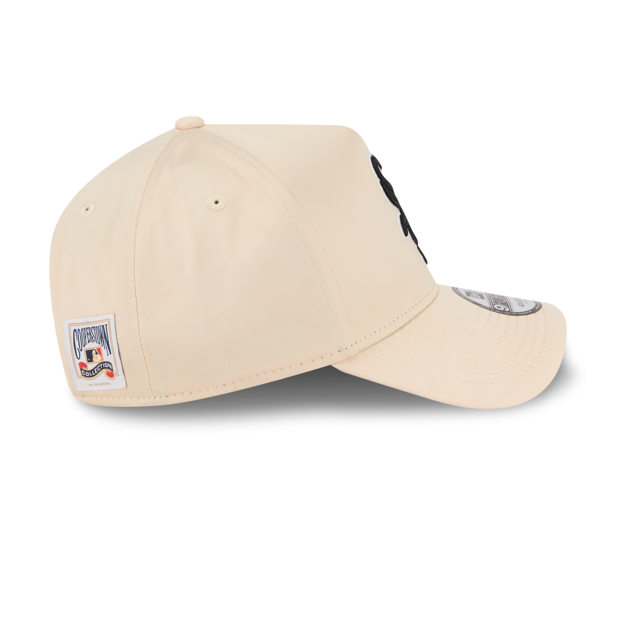A beige baseball cap shown from a three-quarters angle on a white background, featuring a side patch with a cartoon character and a silver New Era 9FIFTY sticker on the brim.