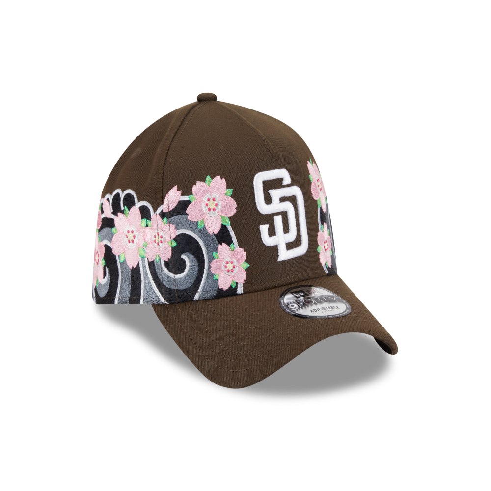 A brown baseball cap featuring a white embroidered 'SD' logo and pink cherry blossoms with gray scrollwork on the side panels, shown against a plain white background.