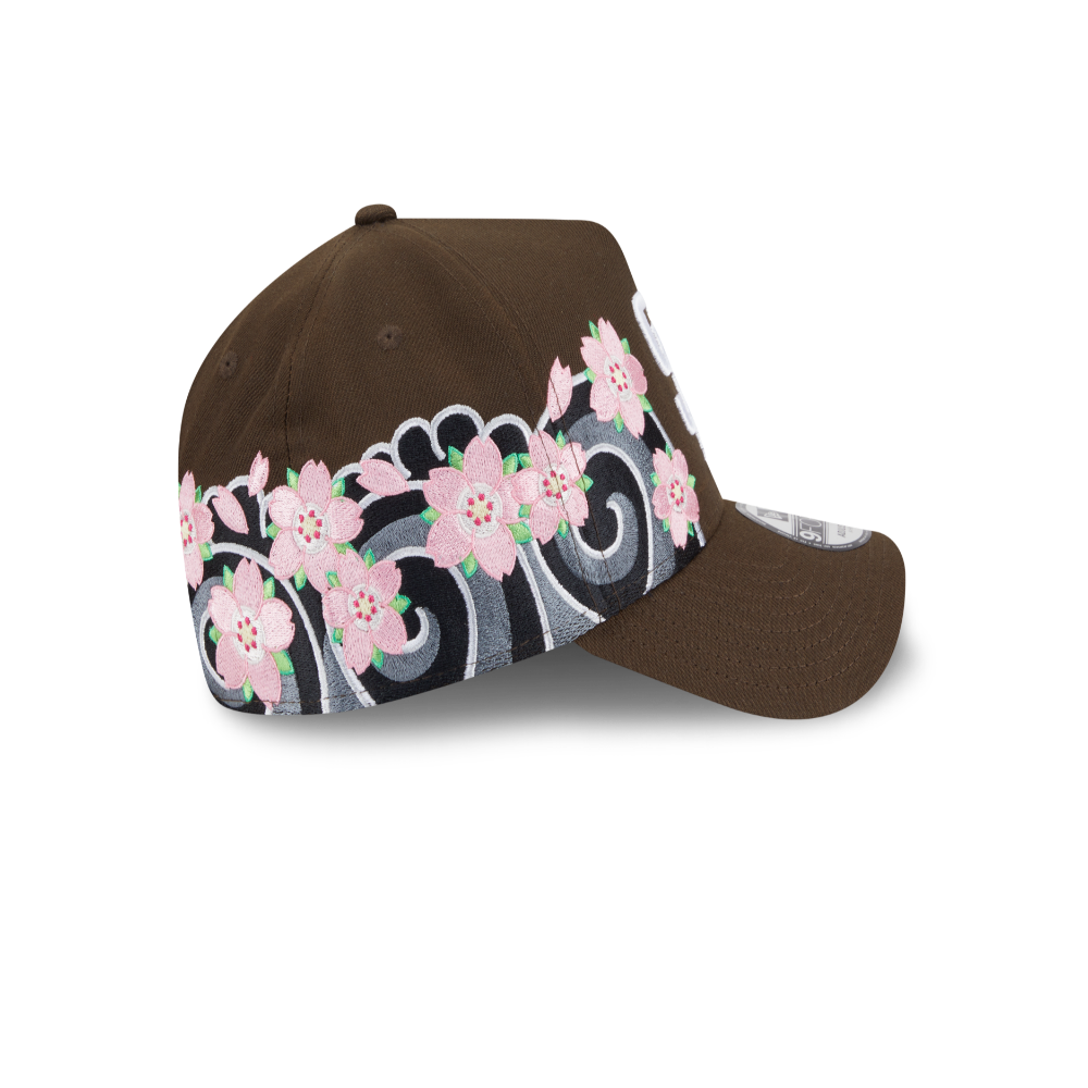 A brown baseball cap featuring a decorative band of pink cherry blossoms and gray scrollwork on the side panels, shown against a plain white background.