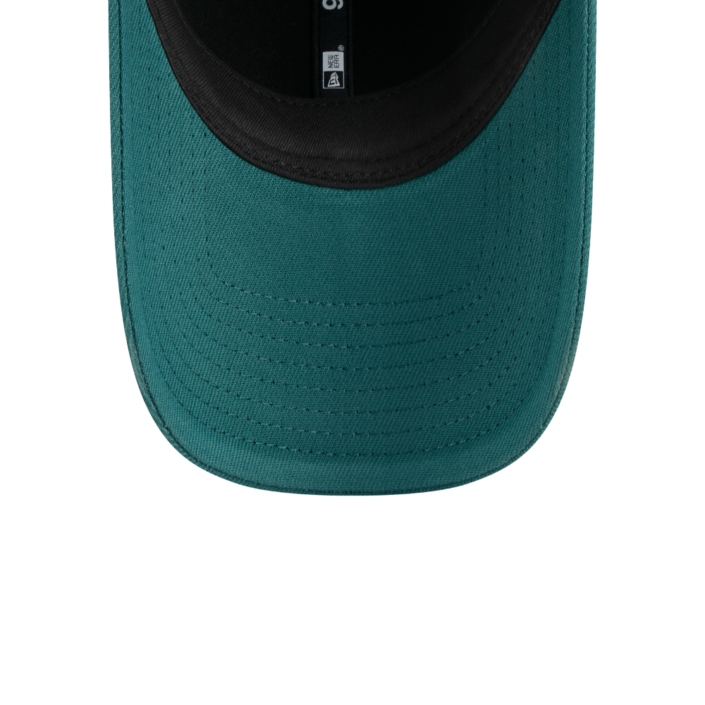 Close-up of the front curved brim of a teal green baseball cap with a black inner lining, showing the fabric texture and stitching.