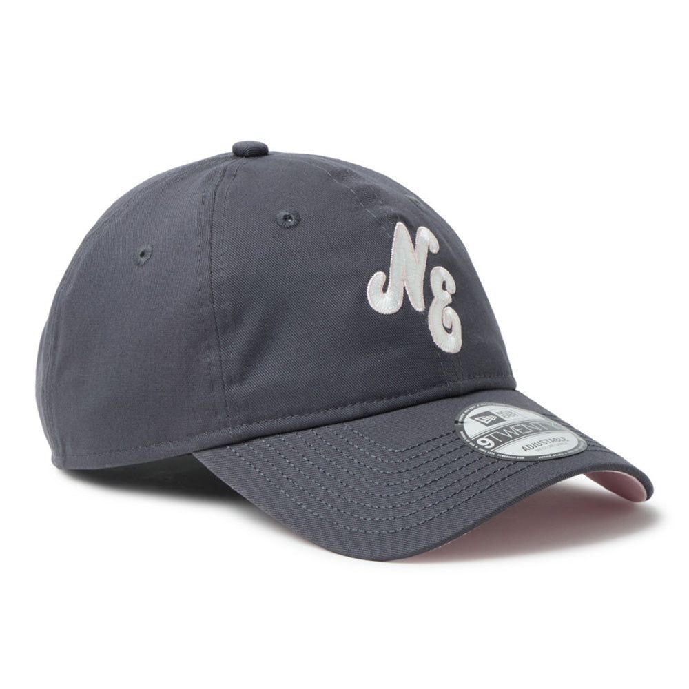 A dark gray baseball cap featuring a white embroidered 'M&G' logo on the front and a silver-toned metal visor sticker, shown on a clean white background.