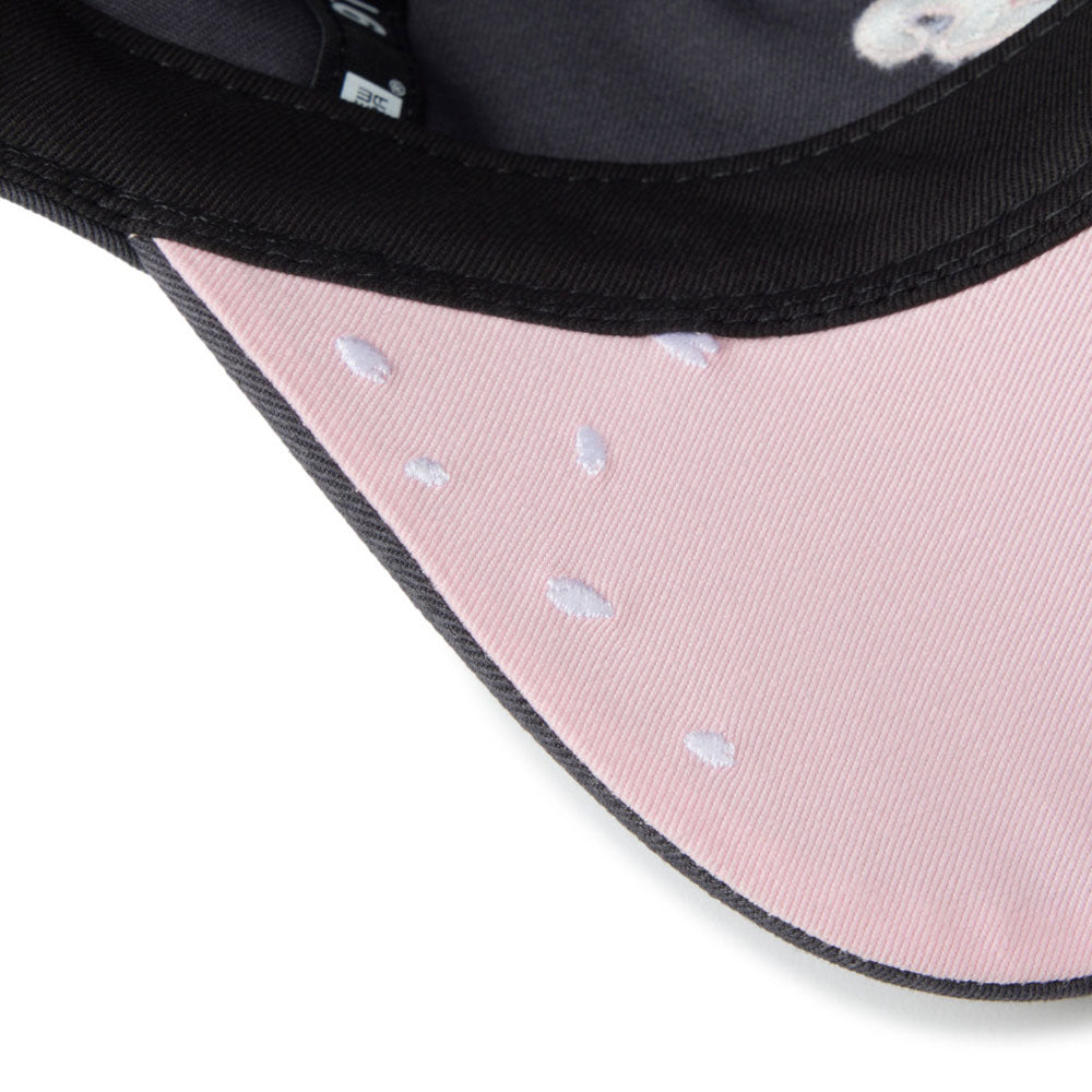 Close-up of a baseball cap showing a light pink visor with white embroidered strawberry details, a black stitched edge, and a black interior.