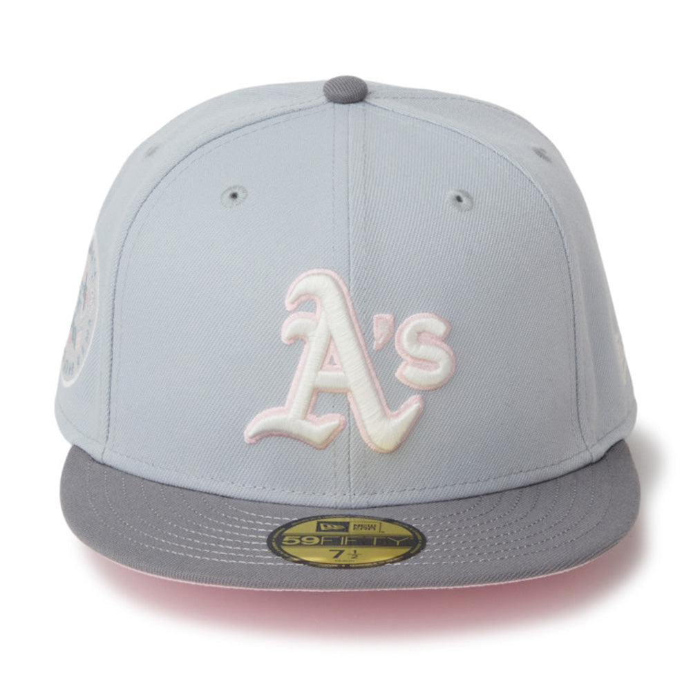 A light gray and dark gray baseball cap featuring an embroidered white and pink 'A's' logo on the front, with a gold New Era 59FIFTY sticker on the visor.
