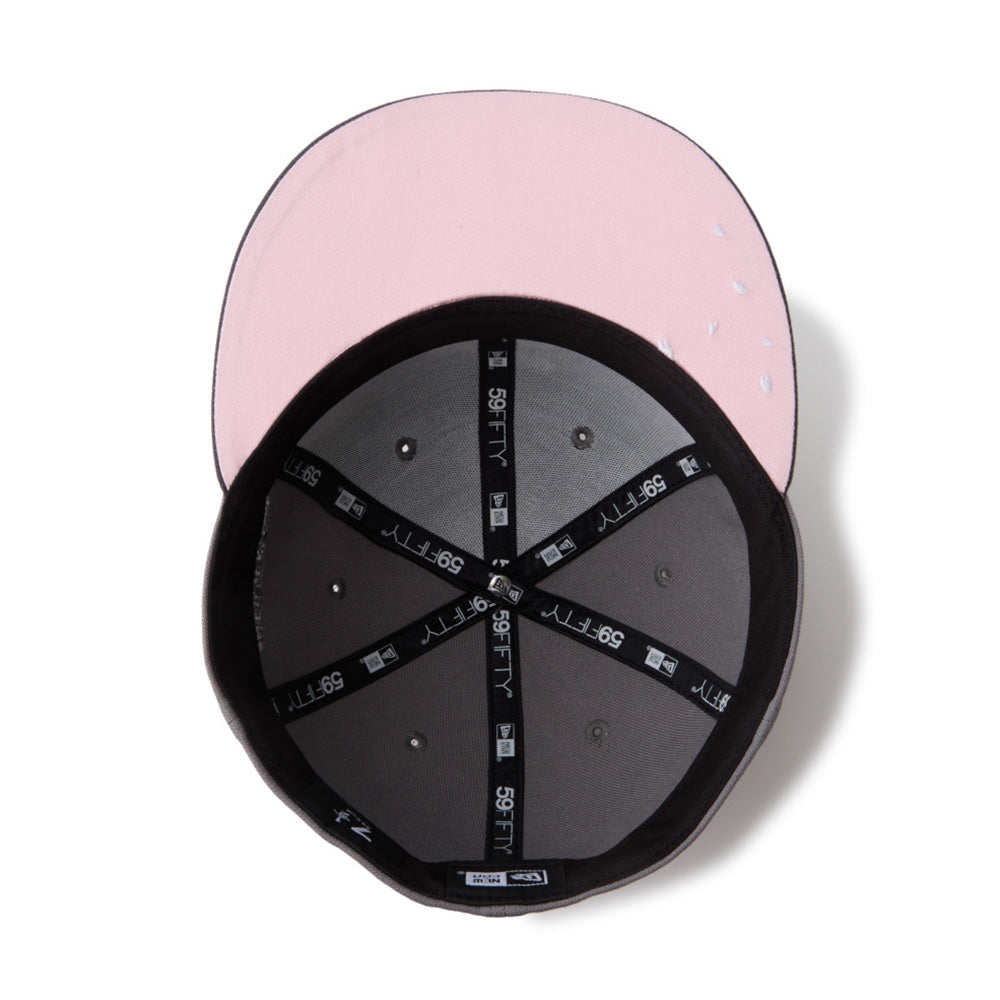 A pink structured baseball cap shown from a top-down angle, with the black interior and adjustable black elastic straps visible against a white background.