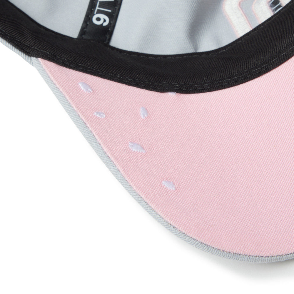 Close-up of a pink cap with black rim and white text on a white background