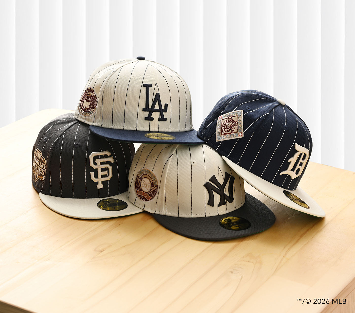 Four baseball caps with different team logos on a wooden surface.