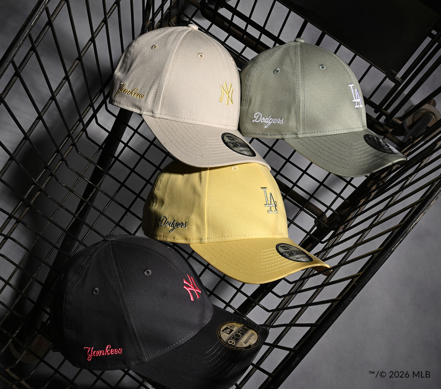 Four baseball caps with different logos on a black shopping cart